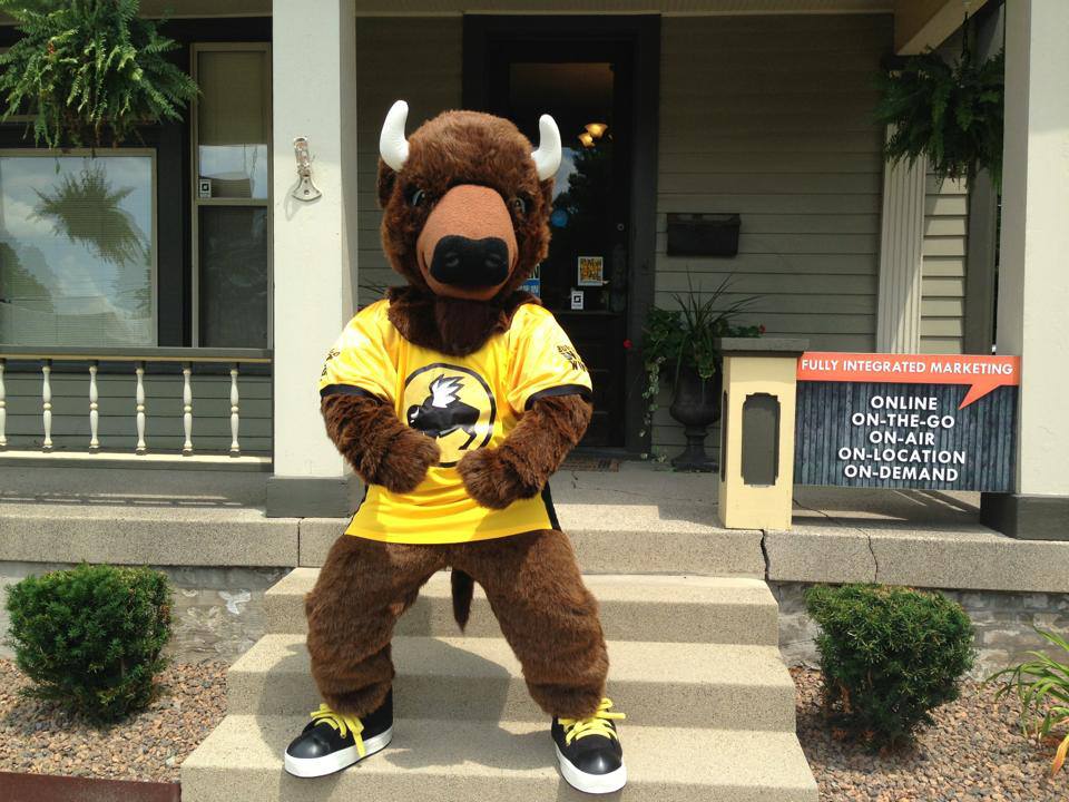 The mascot, promoting our Integrated Marketing Solutions, is wearing a yellow shirt.