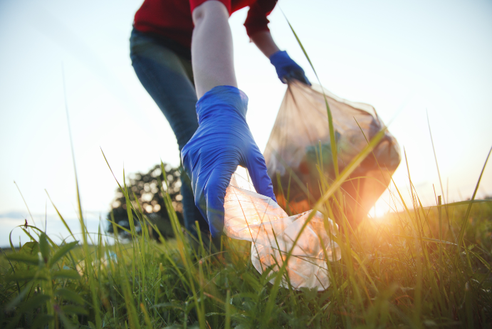 A woman is picking up trash in the grass, part of an Integrated Marketing Solutions campaign by an Indianapolis Marketing Agency.