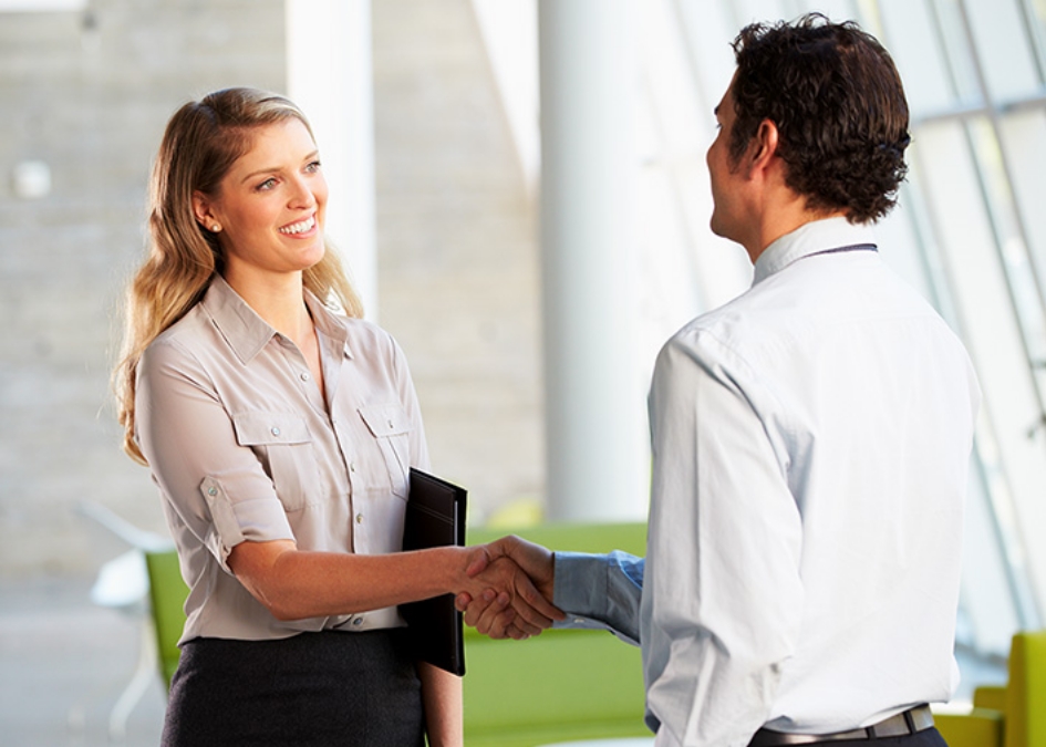 A man and woman shaking hands in an office, signifying integrated marketing solutions.